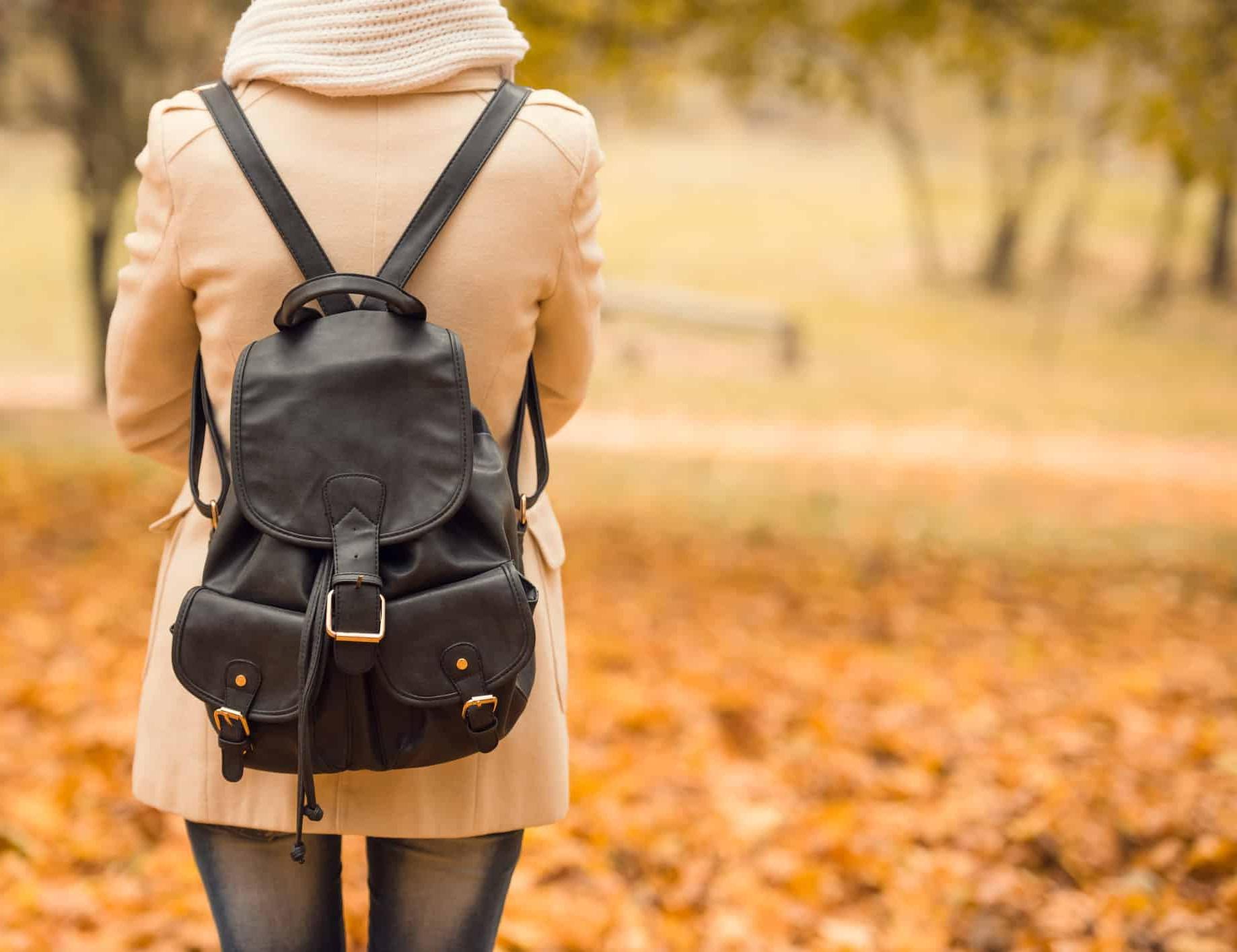 秋天的公园里，背着背包对着镜头的女学生